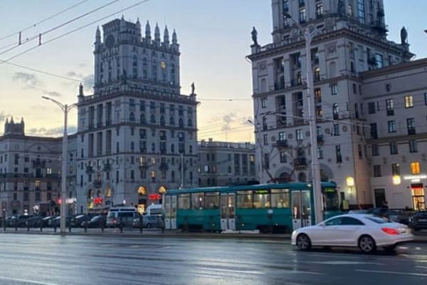 Ворота Минска на Привокзальной площади вечером, перед башнями проезжает троллейбус.
