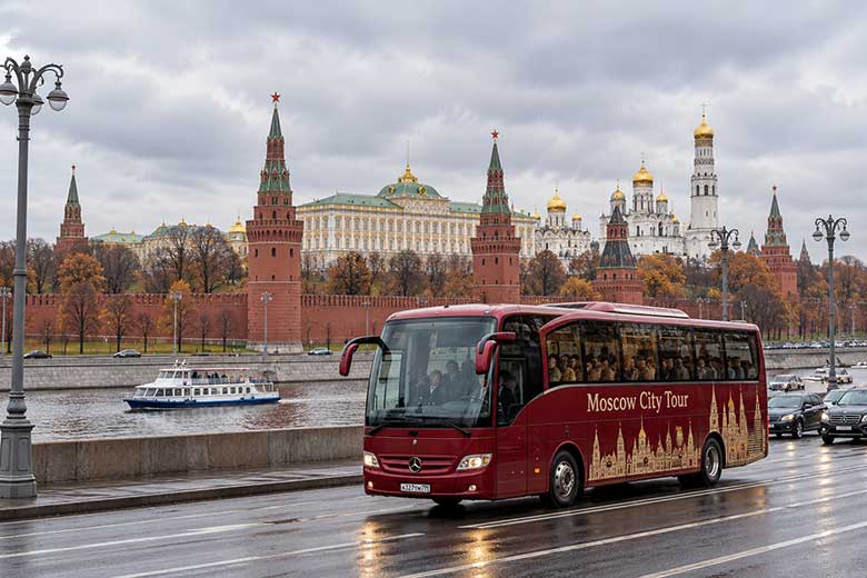 Туристический автобус на набережной Москвы-реки в ноябре на фоне Московского Кремля — обзорная экскурсия по столице.