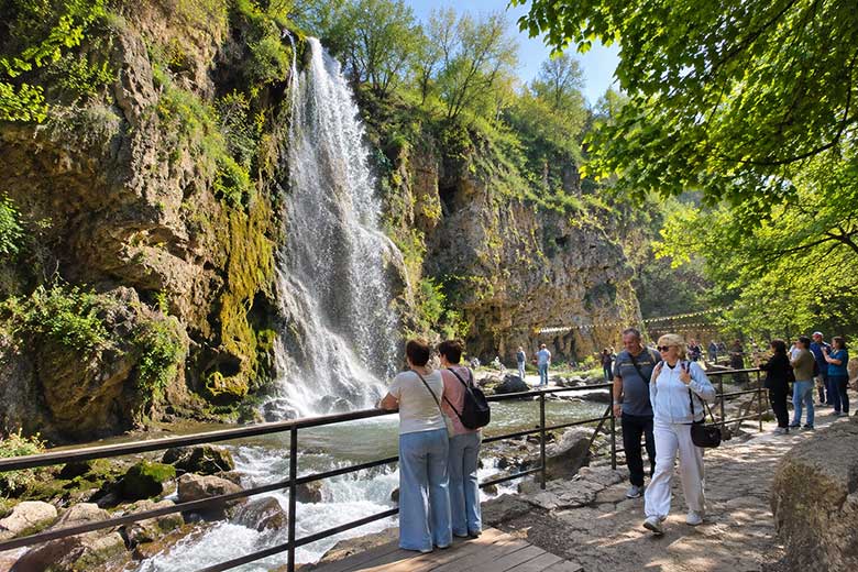 Медовые водопады неподалёку от Кисловодска, каскад воды среди скал и весенней зелени, туристы на смотровой площадке.