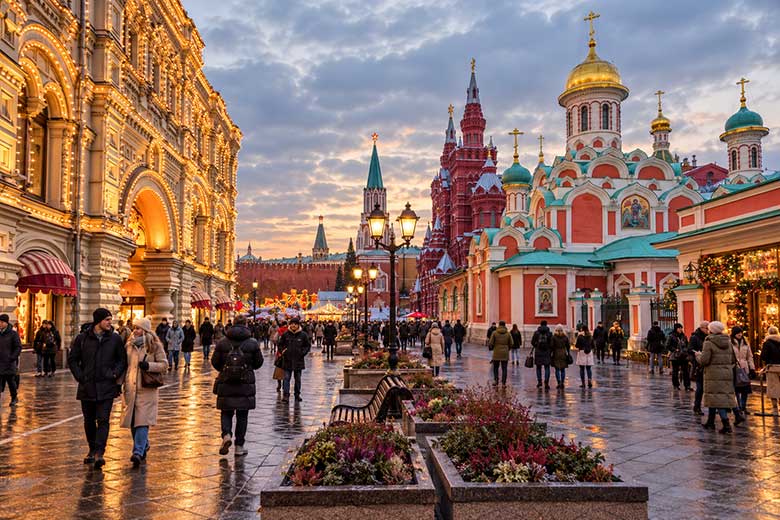Никольская улица в Москве ноябрьским вечером: туристы и прохожие, праздничная подсветка, мокрая брусчатка и исторические здания.